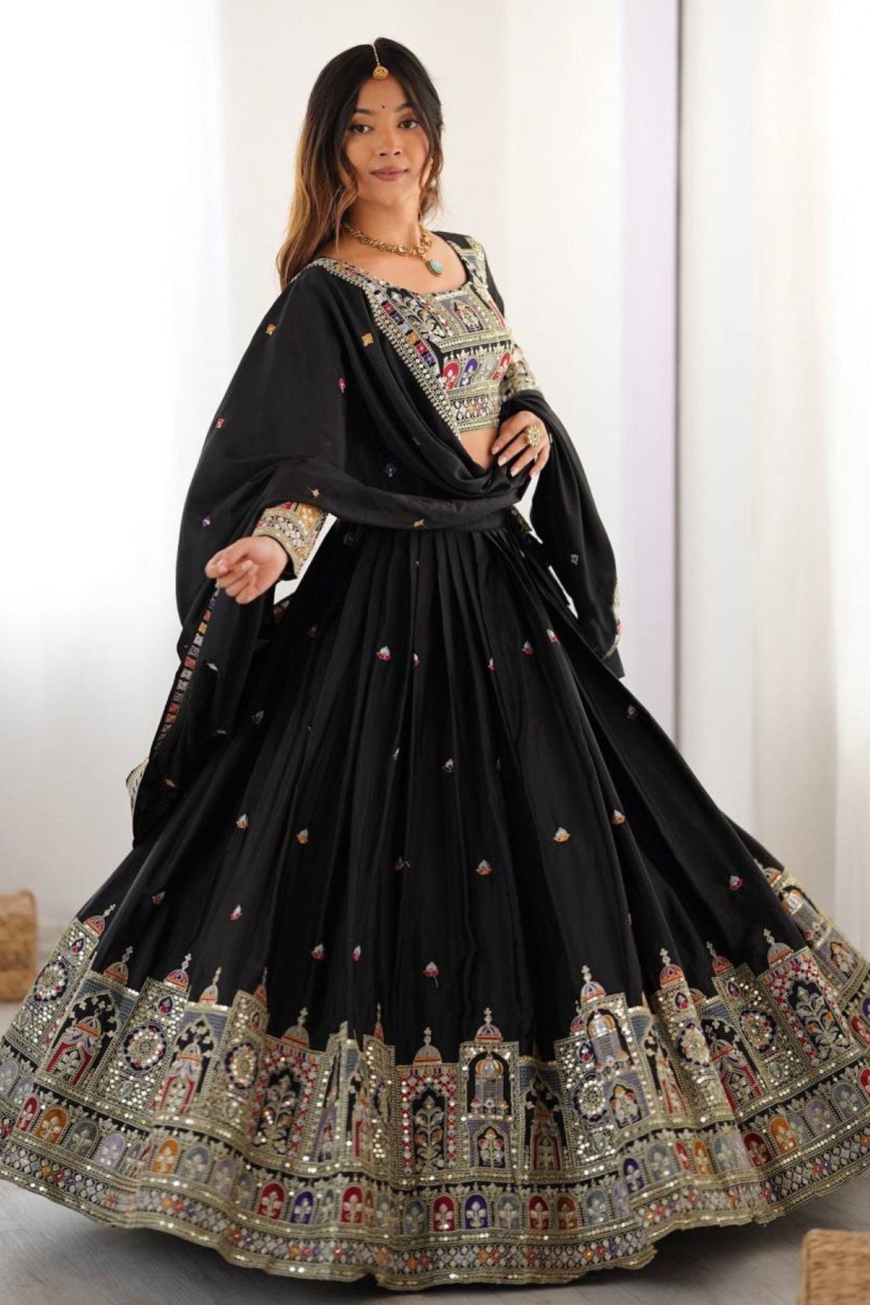 Woman wearing a black embroidered lehenga with a white background