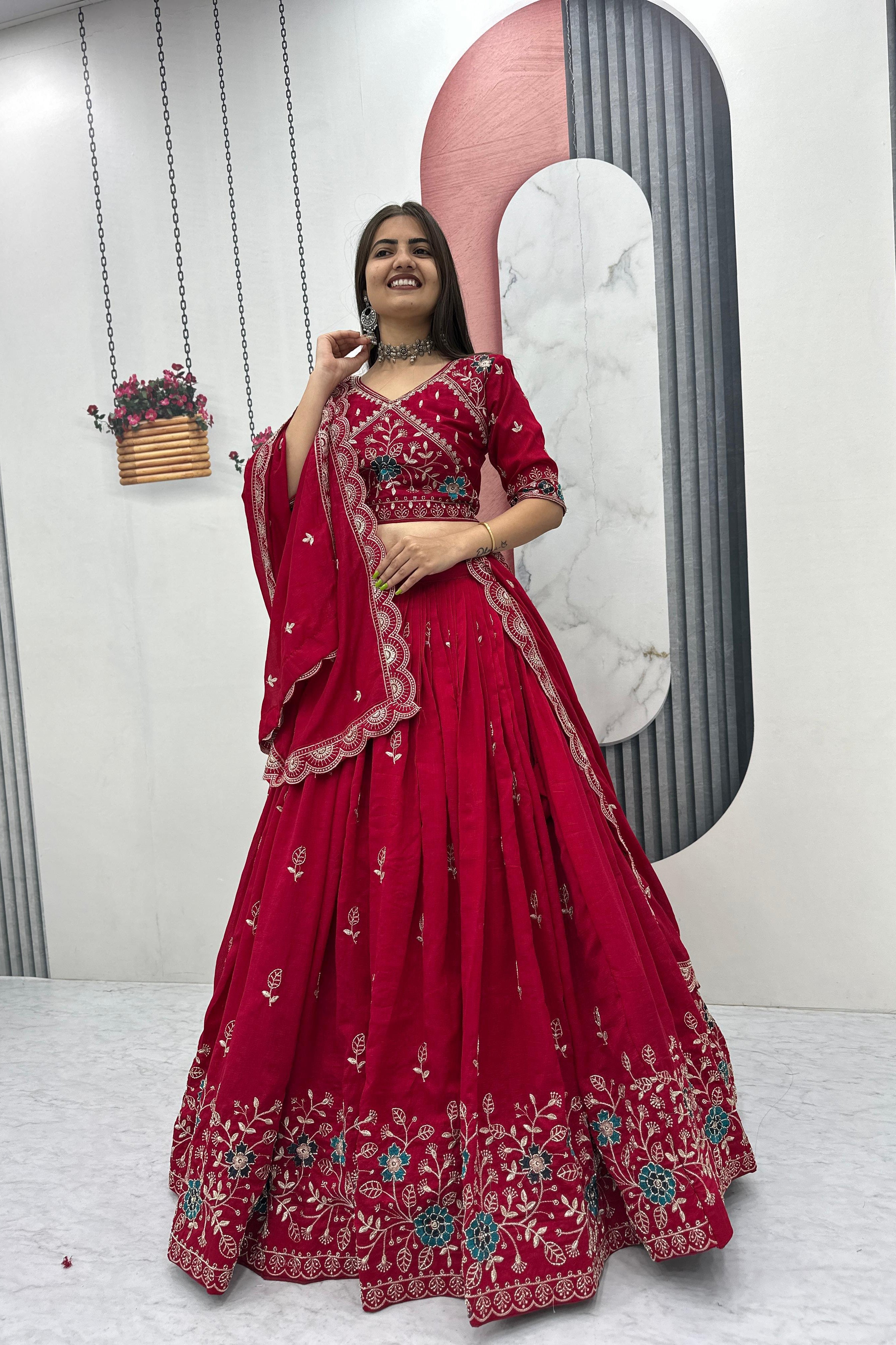 Woman in a red embroidered traditional outfit posing in front of a mirror.