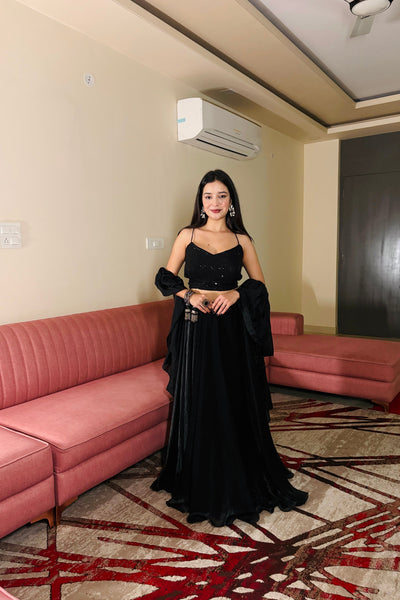 Woman in a black dress standing in a room with pink furniture and a beige wall.