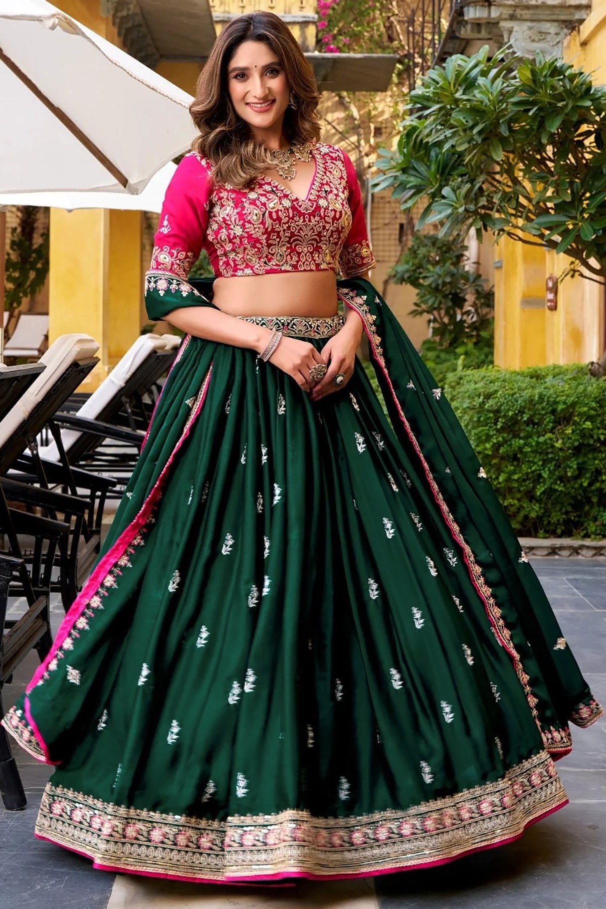 Woman in a green and pink traditional outfit standing outdoors.