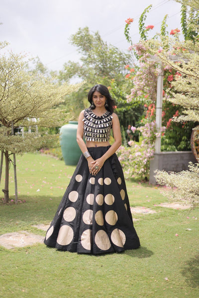 Woman in a black and white patterned outfit standing in a garden.