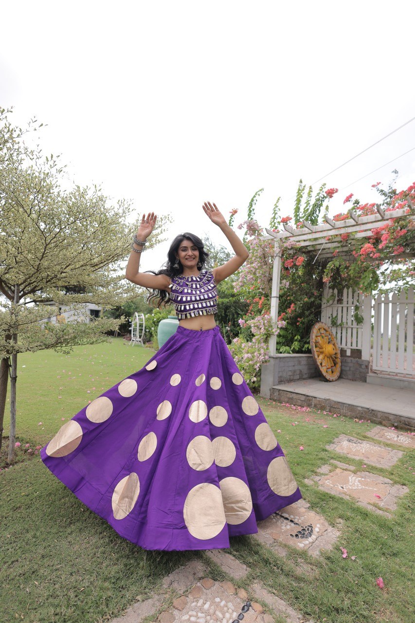 Woman in a purple skirt with gold circles dancing outdoors.