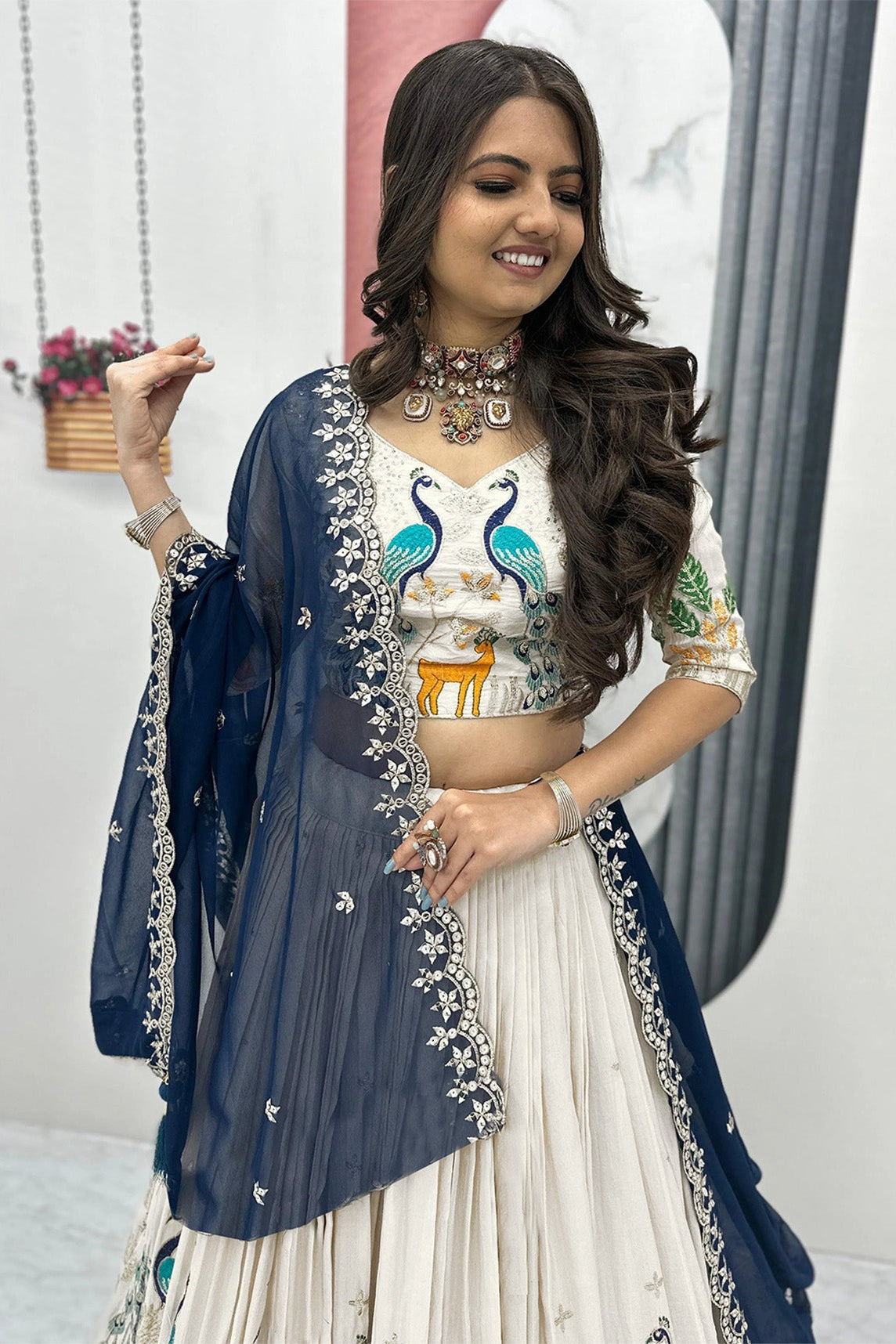 Woman in traditional outfit with embroidered top and white skirt, standing indoors.