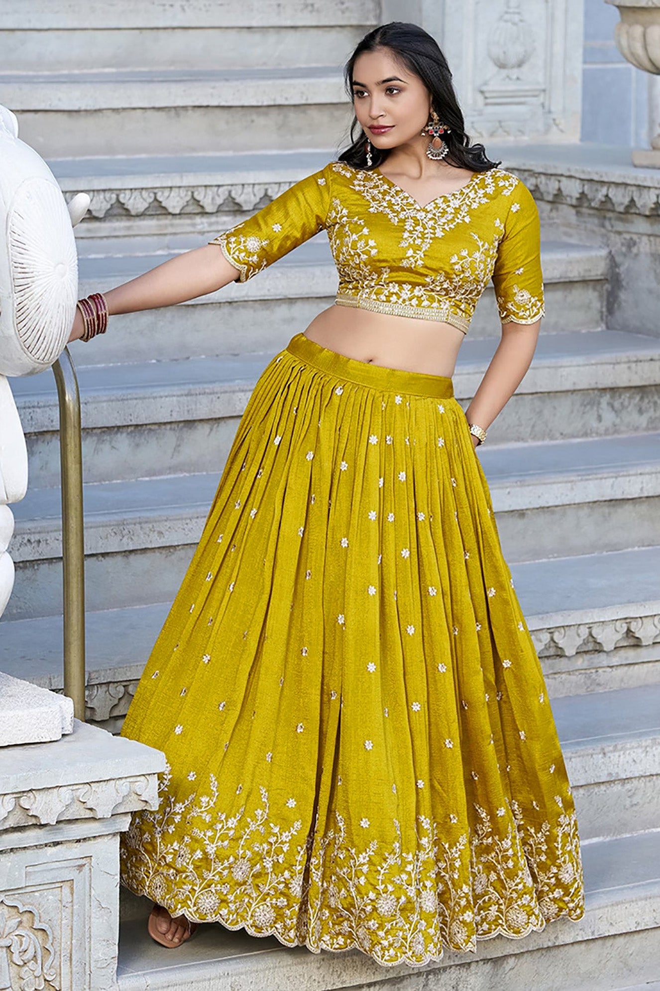 Woman in a yellow traditional outfit standing on stone steps.
