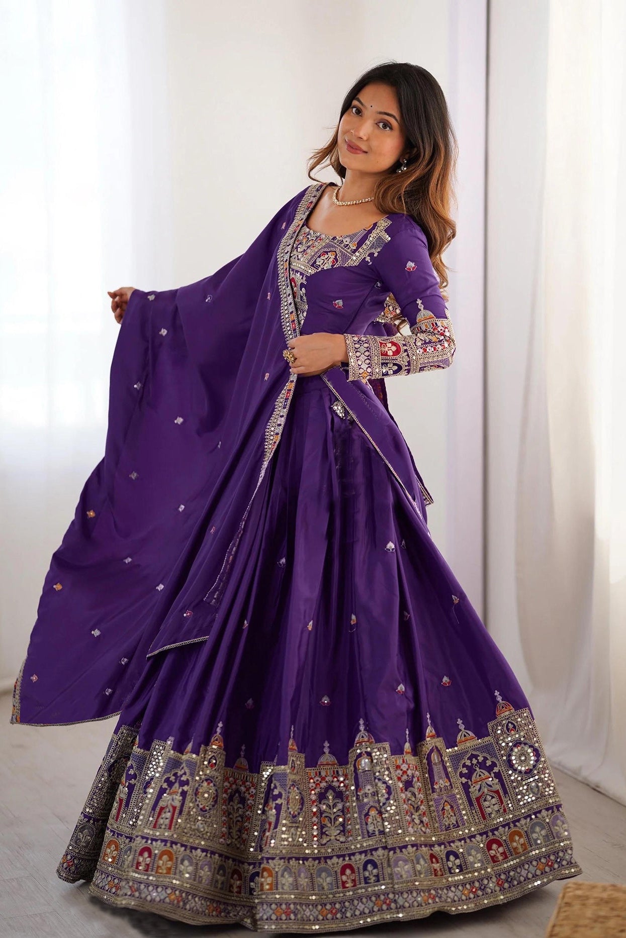 Woman wearing a purple embroidered traditional outfit with a white curtain background