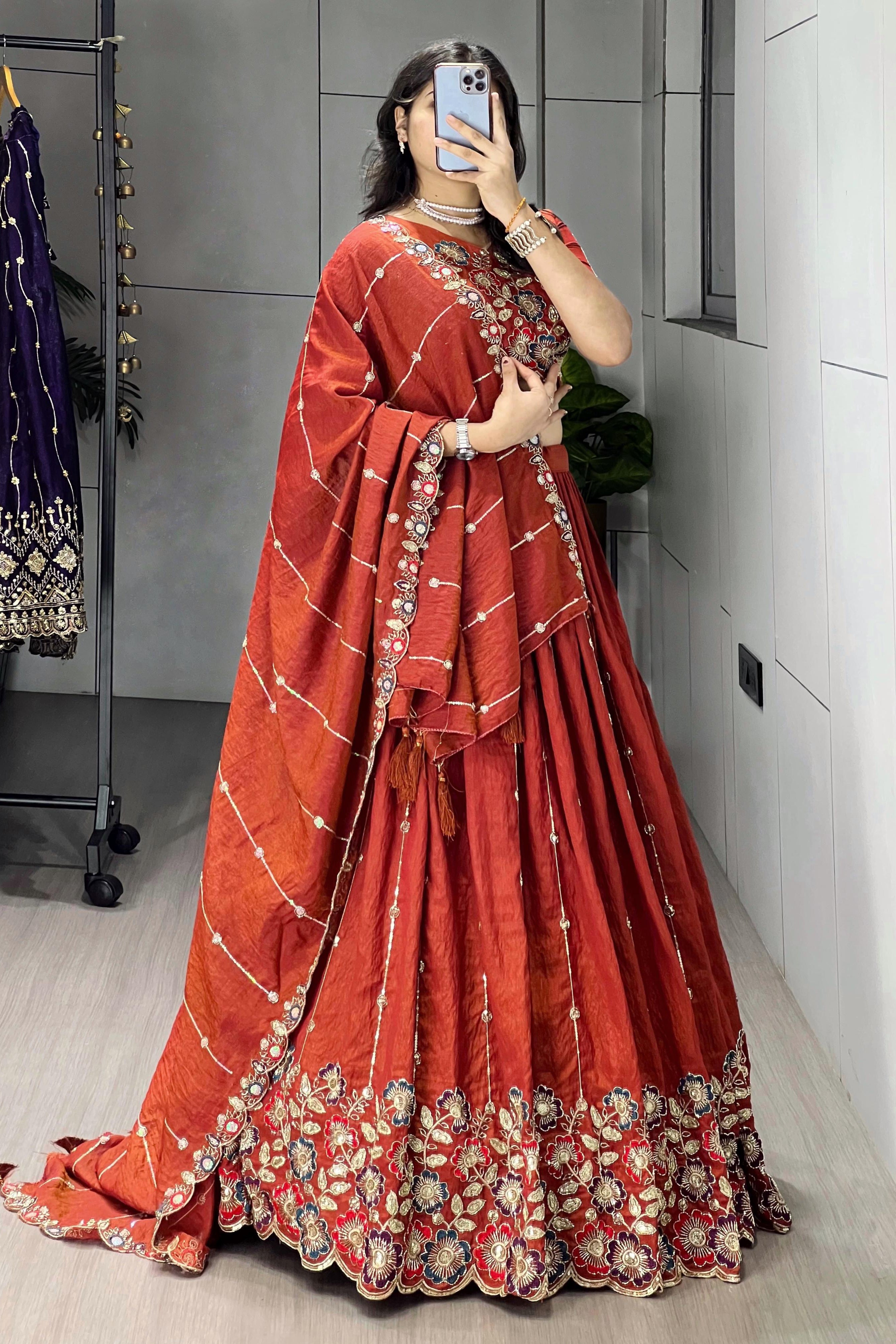 Person wearing a red traditional outfit with floral patterns in a room.