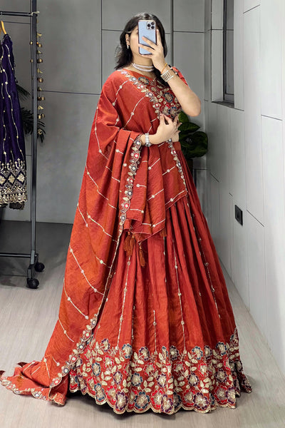 Person wearing a red traditional outfit with floral patterns in a room.