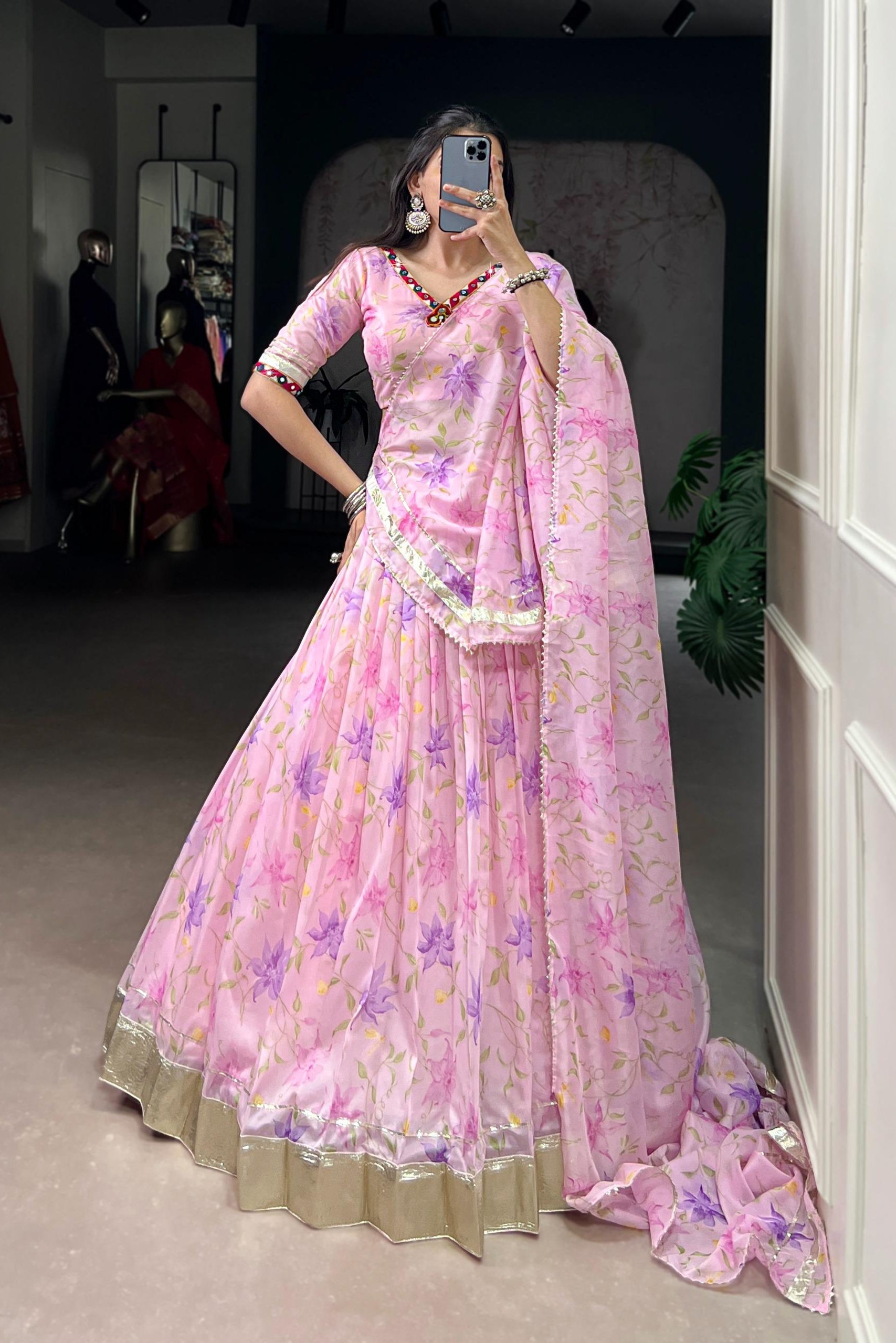 Woman wearing a pink floral saree with a matching blouse in a room setting.