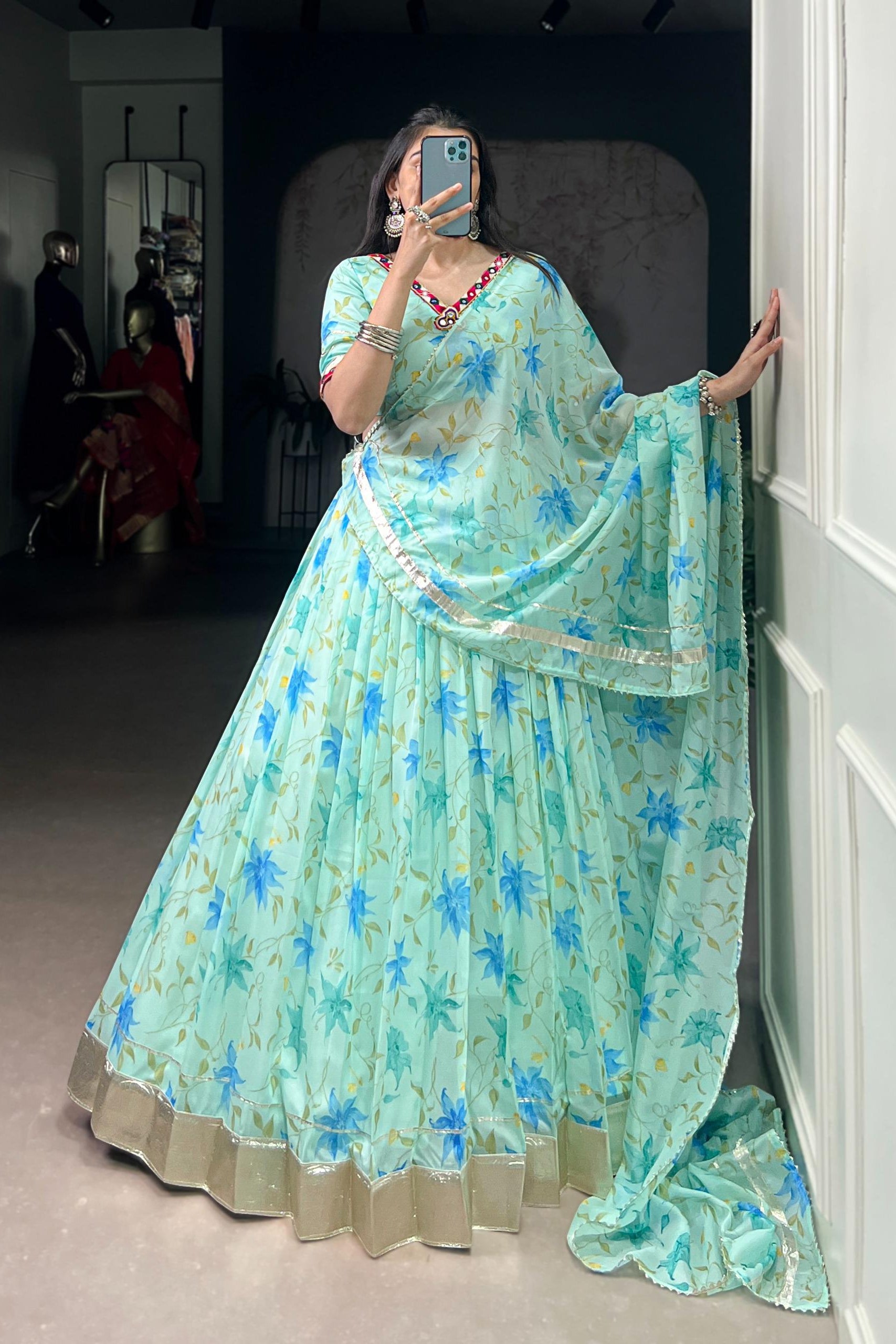 Person wearing a light blue floral saree in a room.