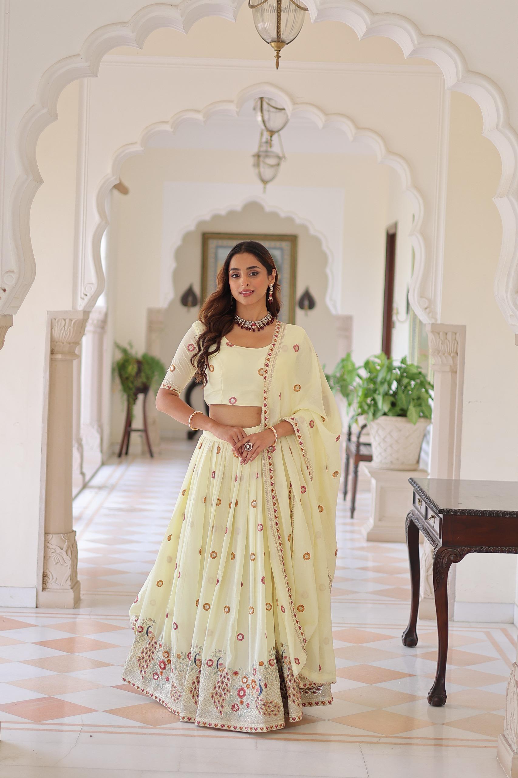 Woman in a light yellow traditional outfit standing in an ornate hall.
